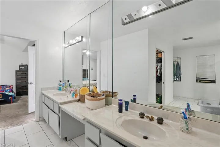 Full bathroom featuring double vanity, a spacious closet, and light tile patterned floors