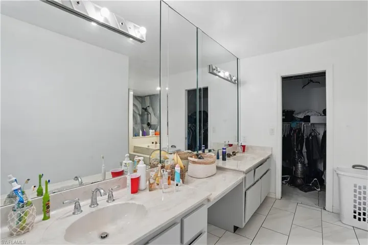 Bathroom featuring double vanity, a walk in closet, and light tile patterned floors