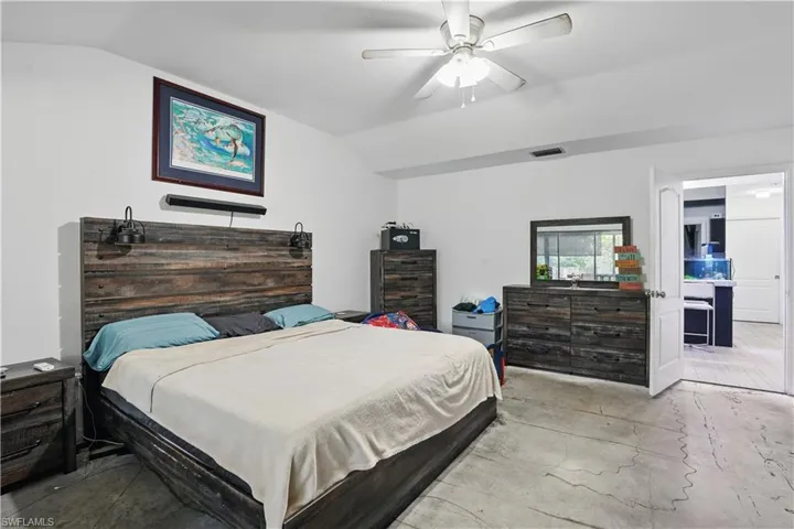 Bedroom with lofted ceiling, ceiling fan, and concrete flooring