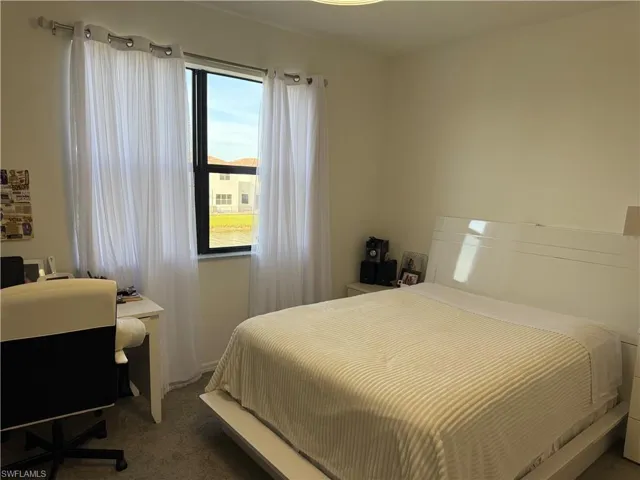 Bedroom featuring dark carpet and an office area