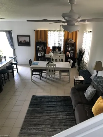 Living room featuring light tile patterned flooring, plenty of natural light, and a ceiling fan