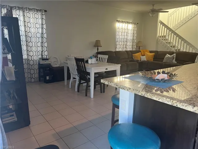 Dining room with stairway, a ceiling fan, and light tile patterned floors