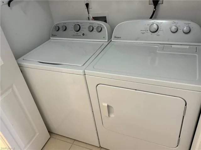 Laundry room with light tile patterned flooring and washer and clothes dryer