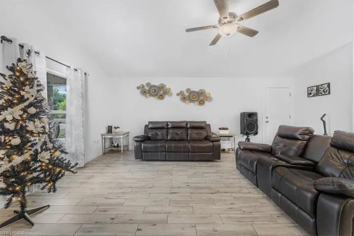 Living area featuring lofted ceiling, ceiling fan, and wood finished floors