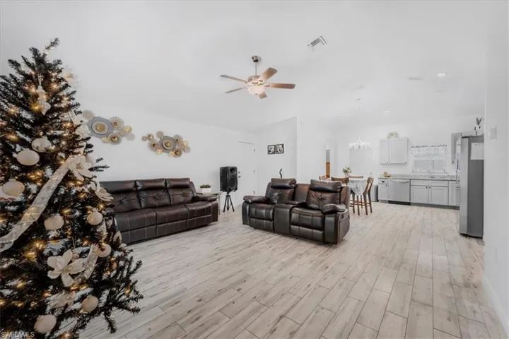 Living area featuring wood tiled floors, hanging lights, and ceiling fan