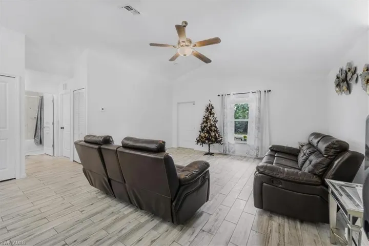 Living area featuring wood tiled floors, ceiling fan, and lofted ceiling