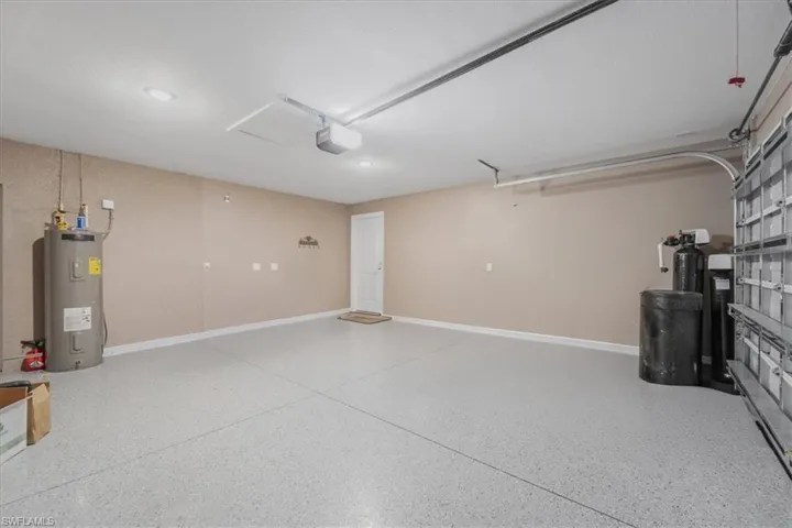 Garage featuring electric water heater and a garage door opener