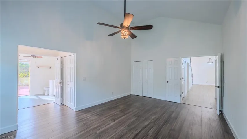 Unfurnished bedroom with a closet, dark wood-type flooring, a ceiling fan, and vaulted ceiling