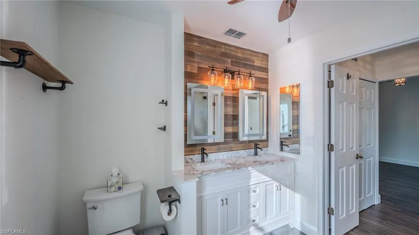 Bathroom with double vanity, ceiling fan, and wood finished floors