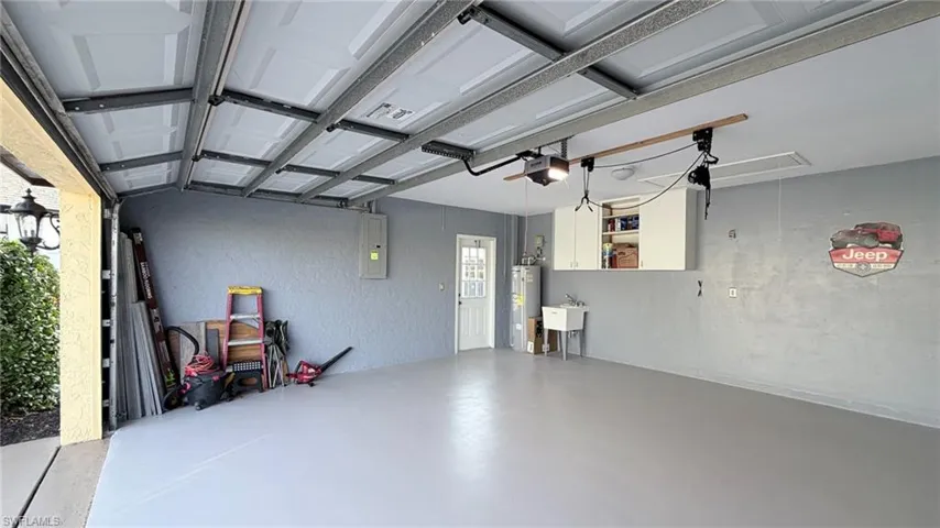 Garage with a textured wall, electric water heater, and electric panel