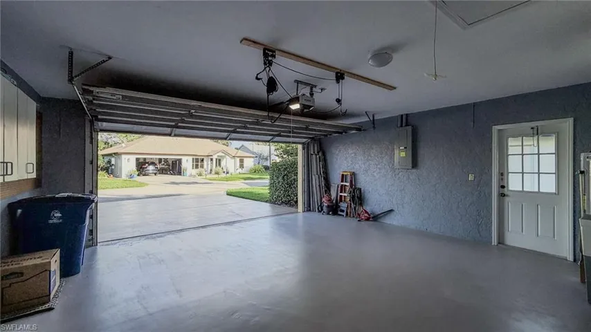 Garage featuring a textured wall, a residential view, electric panel, and a garage door opener