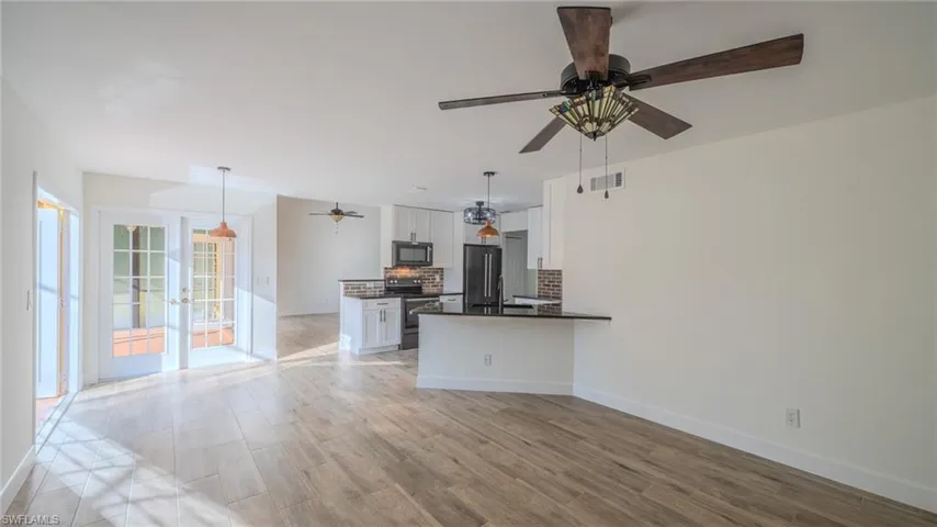 Kitchen with white cabinetry, stainless steel appliances, light wood finished floors, a peninsula, and a ceiling fan
