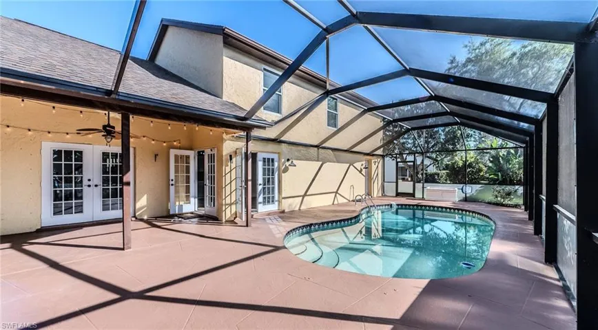 Swimming pool with french doors, a patio area, a sunroom, and a lanai