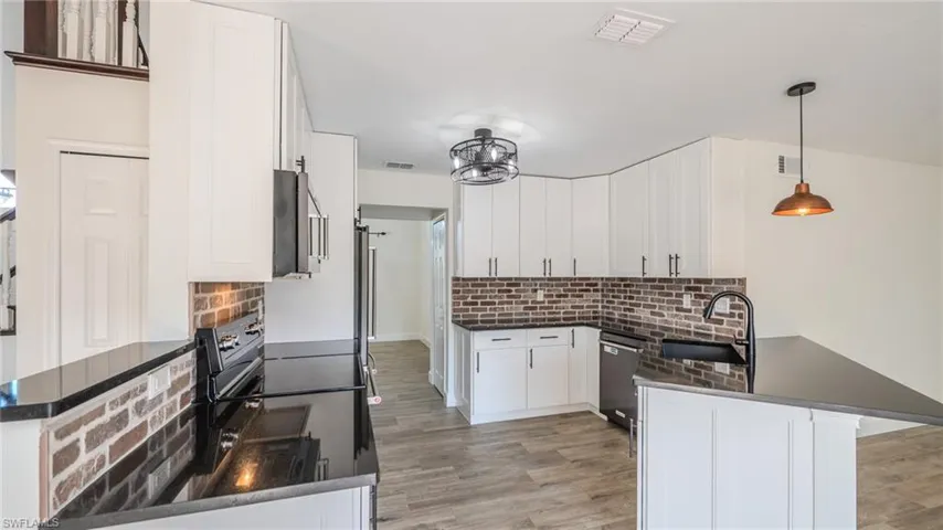 Kitchen featuring a peninsula, white cabinetry, pendant lighting, and stainless steel appliances