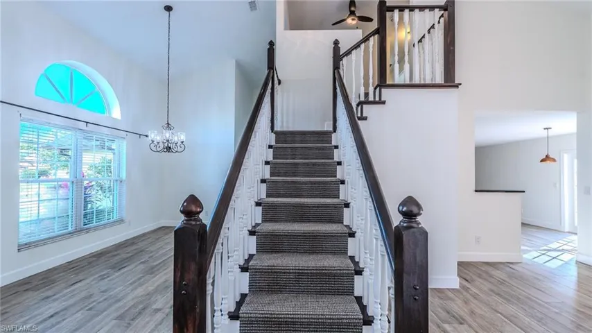 Stairway with a high ceiling, wood finished floors, suspended lighting, and ceiling fan