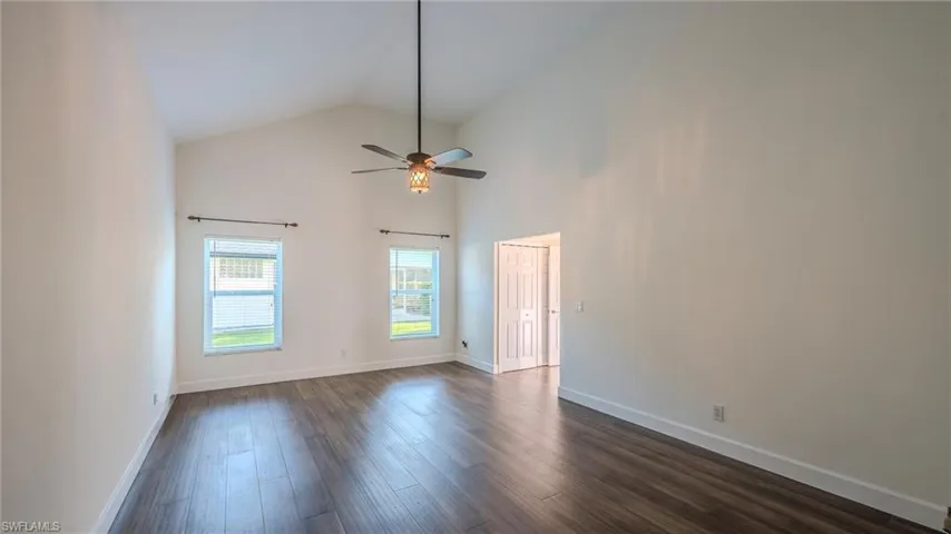 Unfurnished room with lofted ceiling, dark wood-style floors, and a ceiling fan