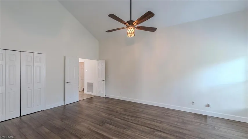 Unfurnished bedroom featuring dark wood-style floors, a ceiling fan, a closet, and lofted ceiling