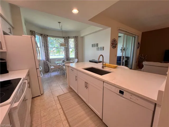 Kitchen featuring sink, white cabinets, pendant lighting, white appliances, and light tile patterned flooring