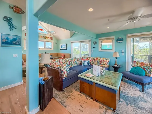 Living area featuring a healthy amount of sunlight, vaulted ceiling with beams, a ceiling fan, and wood finished floors