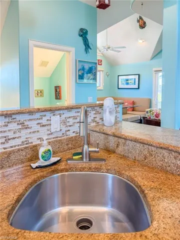 Kitchen featuring ceiling fan, a sink, visible vents, vaulted ceiling, and tasteful backsplash