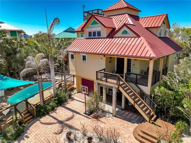 Back of property with a standing seam roof, covered porch, metal roof, and stairway