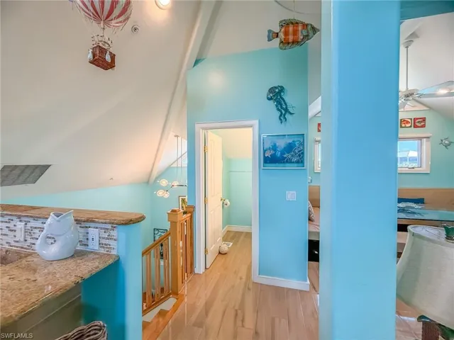 Hallway featuring lofted ceiling, an upstairs landing, light wood-style flooring, and baseboards