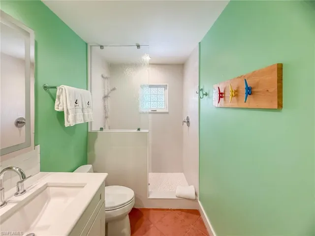 Full bathroom featuring toilet, a stall shower, vanity, baseboards, and tile patterned floors
