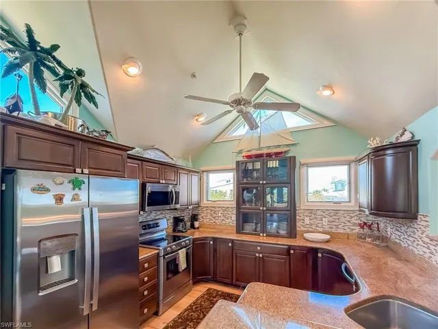 Kitchen featuring decorative backsplash, appliances with stainless steel finishes, vaulted ceiling, dark brown cabinetry, and ceiling fan