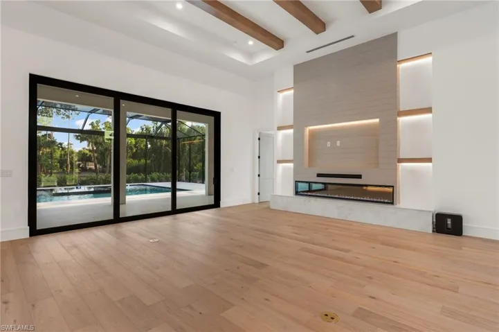 Unfurnished living room featuring baseboards, light wood-type flooring, a high ceiling, visible vents, and beamed ceiling
