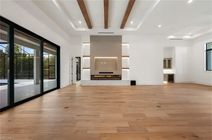 Unfurnished living room featuring recessed lighting, light wood-style flooring, baseboards, and beam ceiling