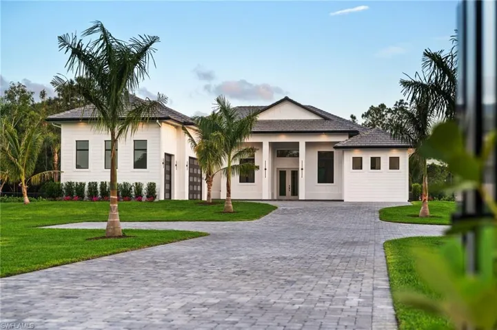 View of front facade featuring a front yard, french doors, and curved driveway