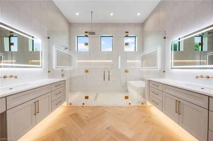 Bathroom featuring a stall shower, two vanities, a sink, and a freestanding bath