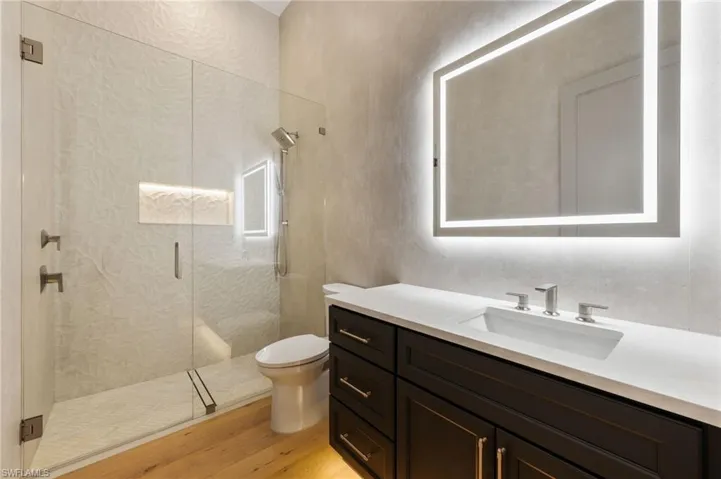 Bathroom with a shower stall, wood finished floors, vanity, and toilet
