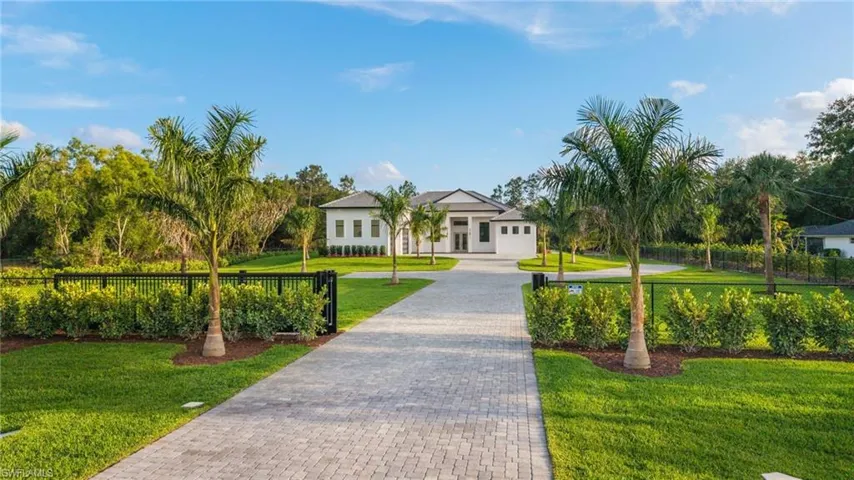 View of front of property featuring a front yard, fence, and decorative driveway
