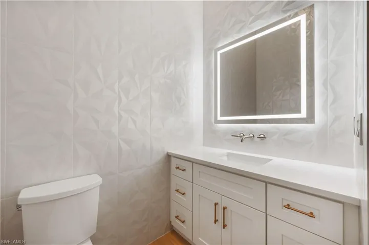 Bathroom with toilet, vanity, and tile walls