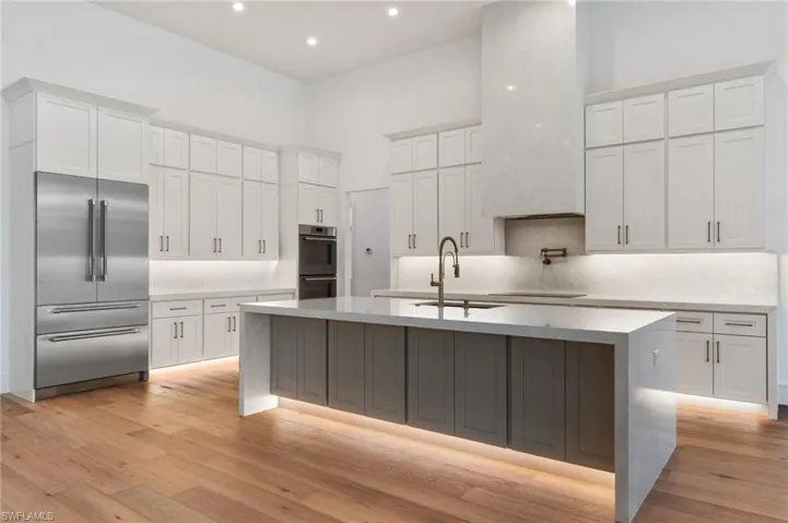 Kitchen with white cabinetry, light wood finished floors, a spacious island, and stainless steel appliances
