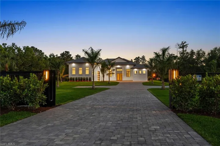 View of front of house with a yard, fence, and curved driveway