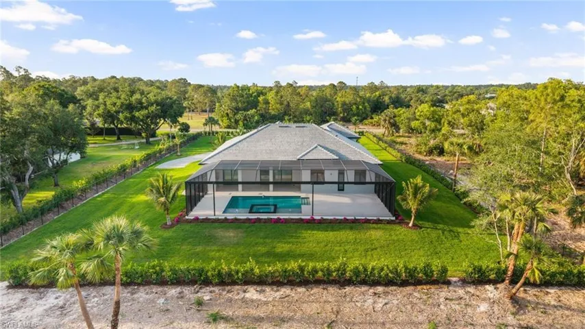 Rear view of property with a patio, an outdoor pool, glass enclosure, and a lawn