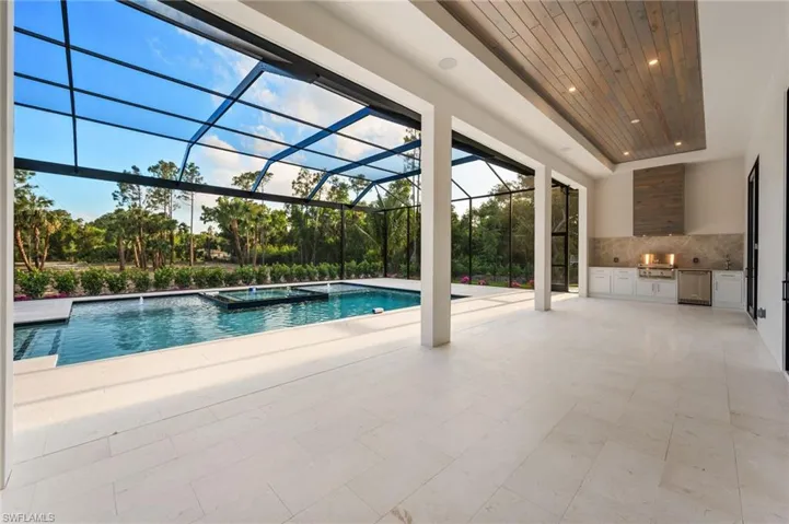 View of pool with area for grilling, a patio area, a pool with connected hot tub, and glass enclosure