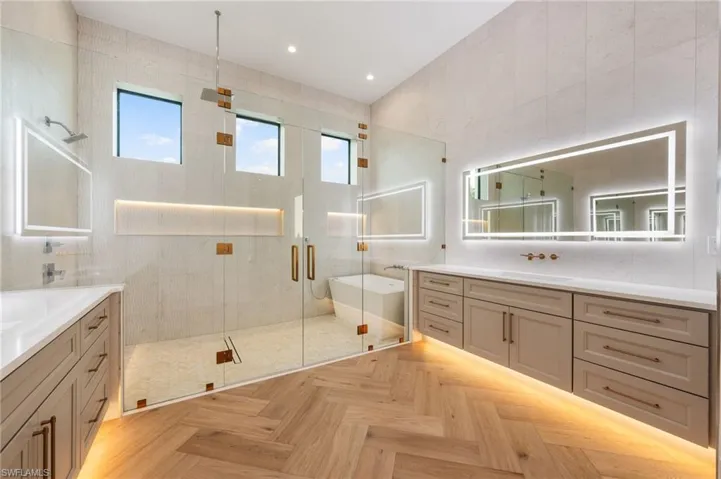 Full bathroom featuring a freestanding tub, a sink, tile walls, two vanities, and a stall shower