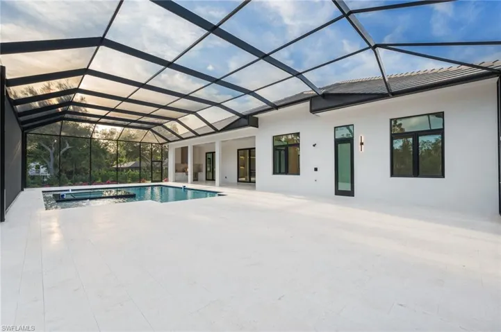 View of pool with a patio area, a pool with connected hot tub, and glass enclosure