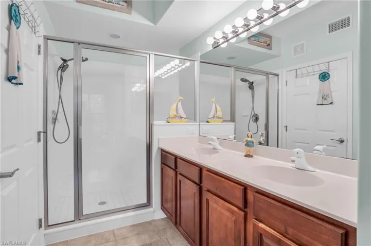 Bathroom featuring walk in shower, dual sinks, tile floors, and oversized vanity
