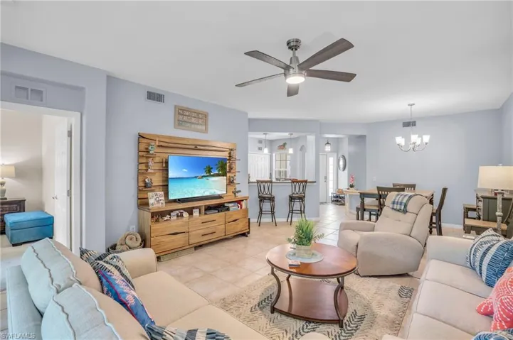 Living room with light tile floors and ceiling fan with notable chandelier
