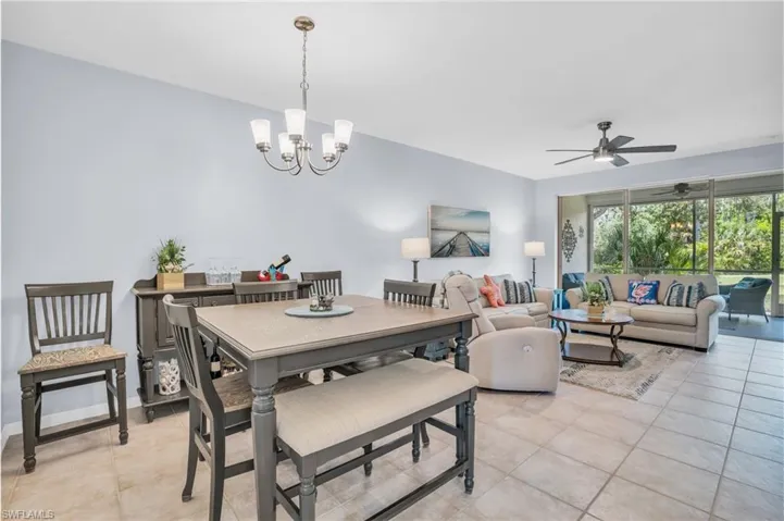 Tiled dining area featuring ceiling fan with notable chandelier