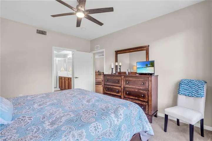 Carpeted bedroom featuring ensuite bathroom and ceiling fan