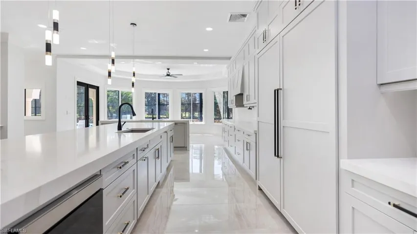 Kitchen featuring paneled built in fridge, light stone countertops, a ceiling fan, decorative light fixtures, and light marble finish flooring