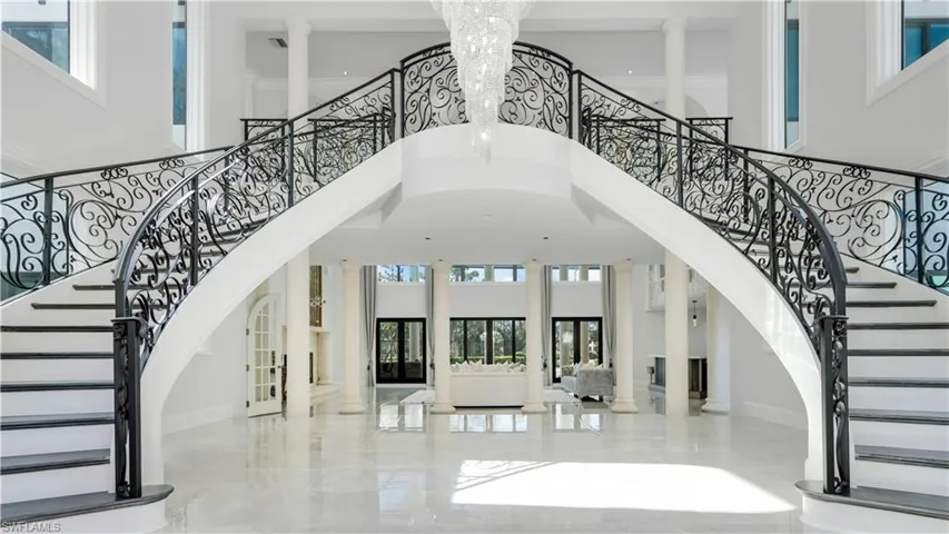 Foyer featuring decorative columns, french doors, a high ceiling, and suspended lighting