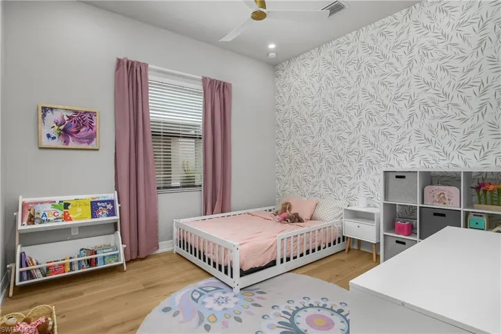 Bedroom with an accent wall, light wood-style flooring, ceiling fan, recessed lighting, and wallpapered walls