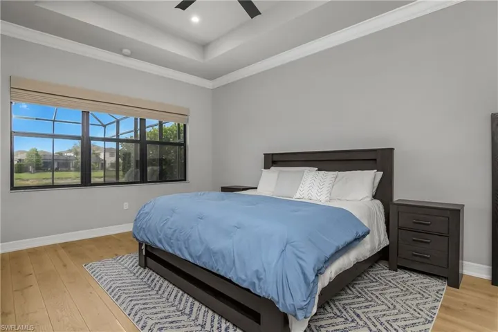 Bedroom with light wood-type flooring, a raised ceiling, crown molding, a ceiling fan, and recessed lighting