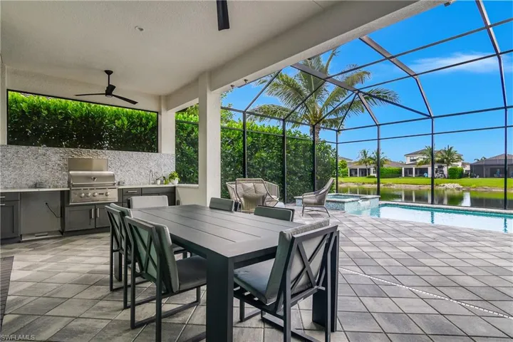 View of patio with area for grilling, a pool with connected hot tub, a sunroom, outdoor dining area, and a ceiling fan